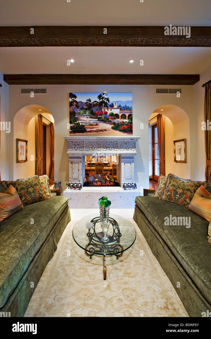 Beautiful living room with opposing green couches and warm fire place Stock Photo