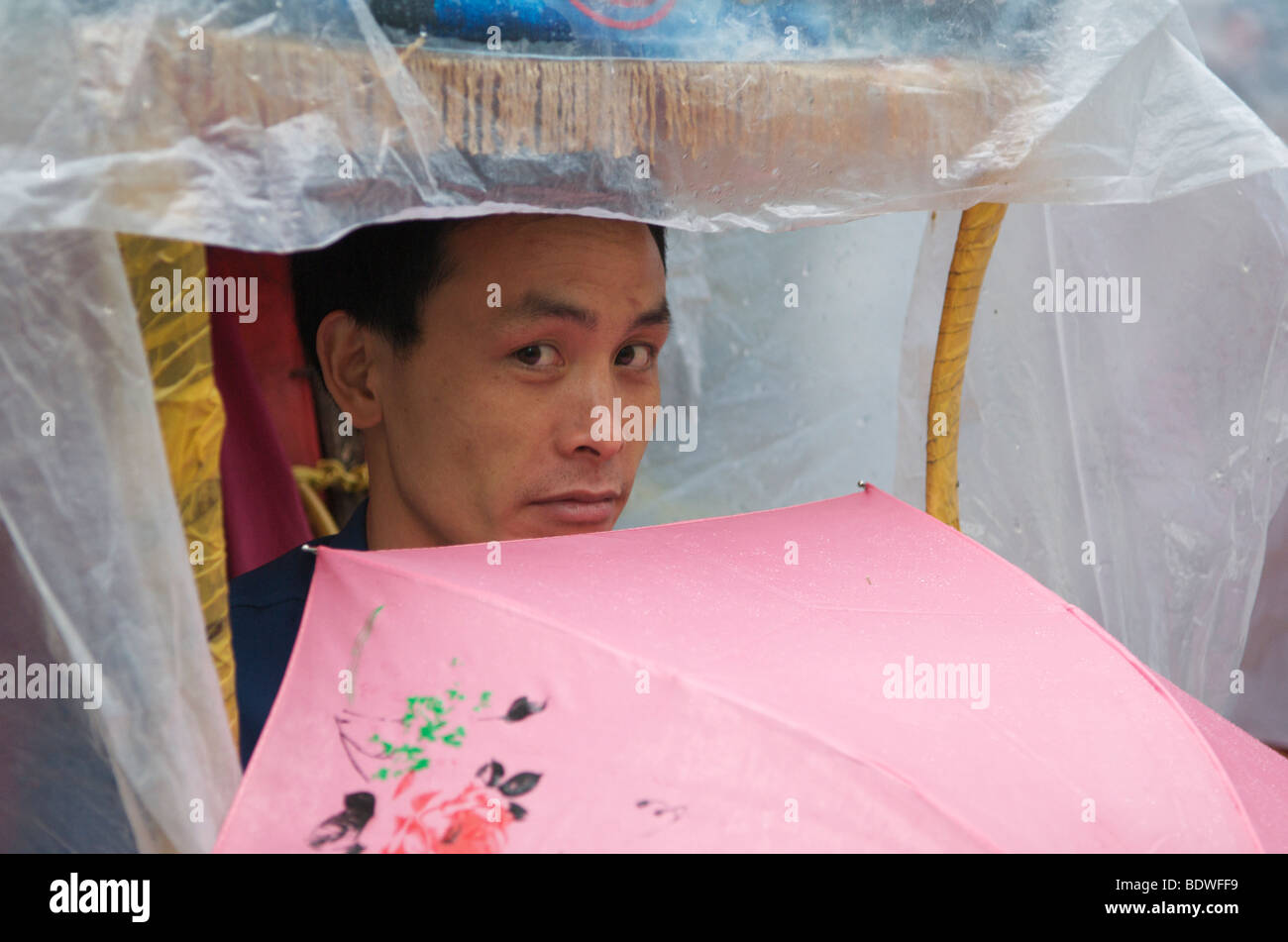 Resting porter waiting in the rain for potential customers Wulingyuan Scenic National Park Hunan Province China Stock Photo