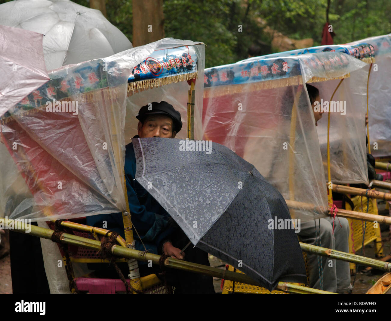 Resting porters waiting in the rain for potential customers Wulingyuan Scenic National Park Hunan Province China Stock Photo