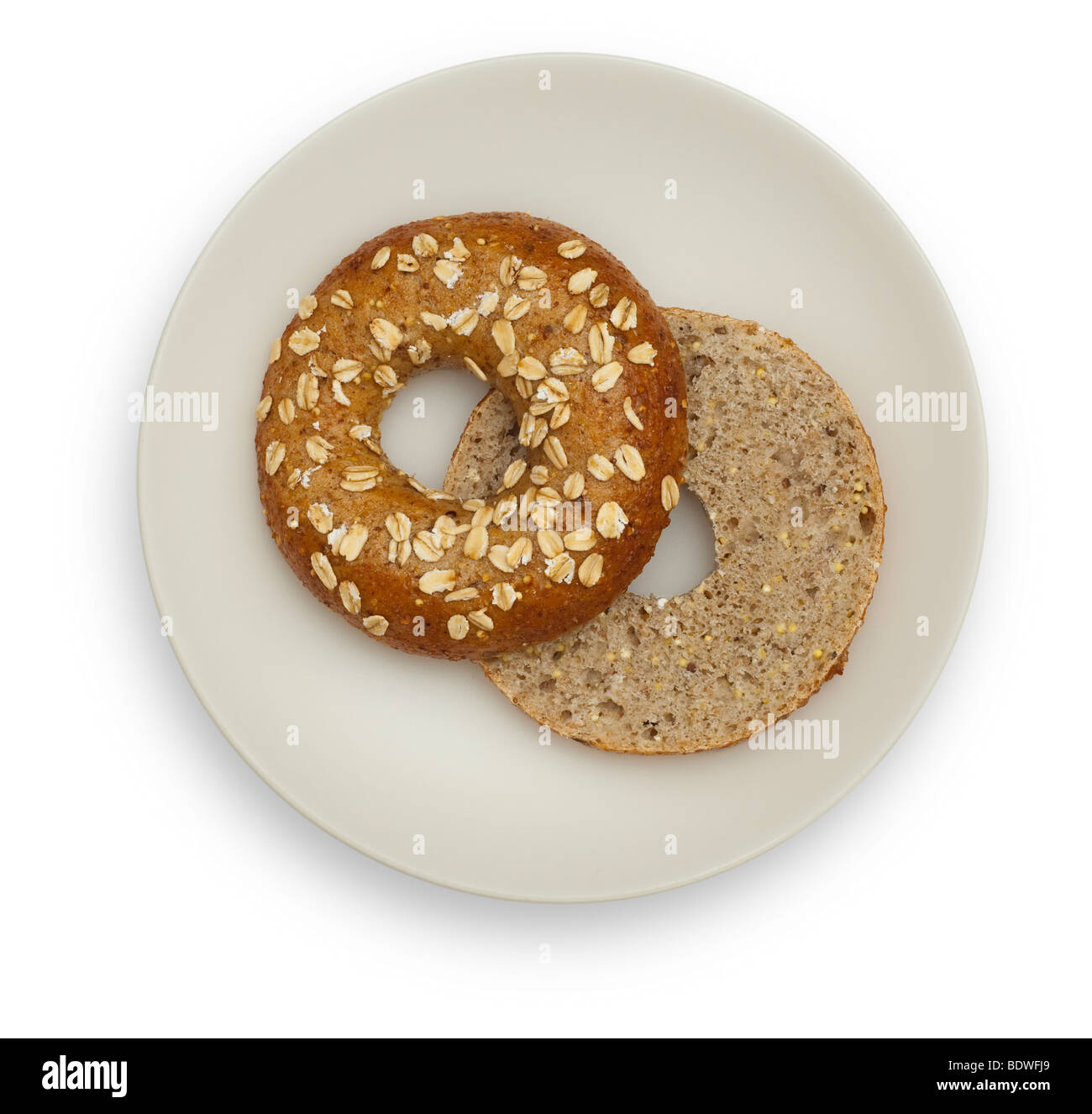 Two halfs of a Whole Grain Bagel on a White plate, isolated on white background. Stock Photo