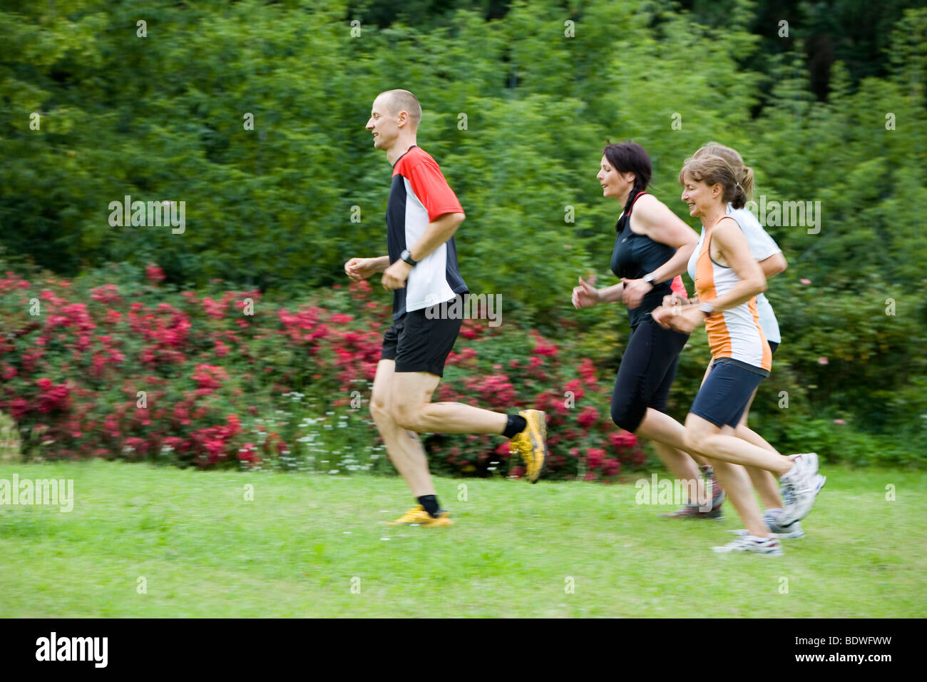 Personal trainer and three women, sprinting outdoors Stock Photo