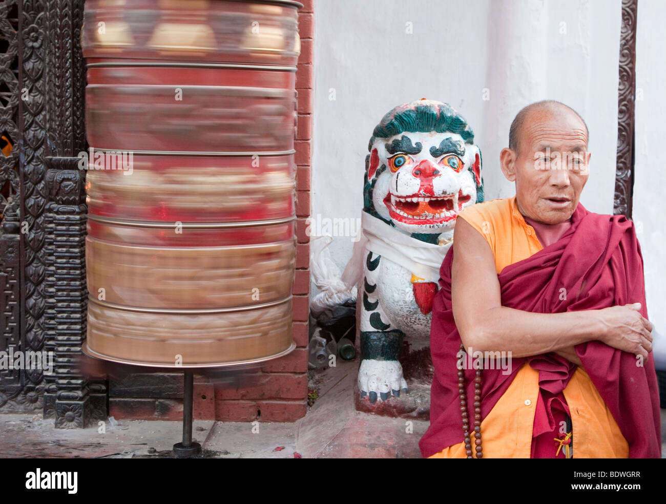 Bodhnath, Nepal. Monk at Entrance to Buddhist Shrine Guarded by Mythical Snow Leopard, Prayer
