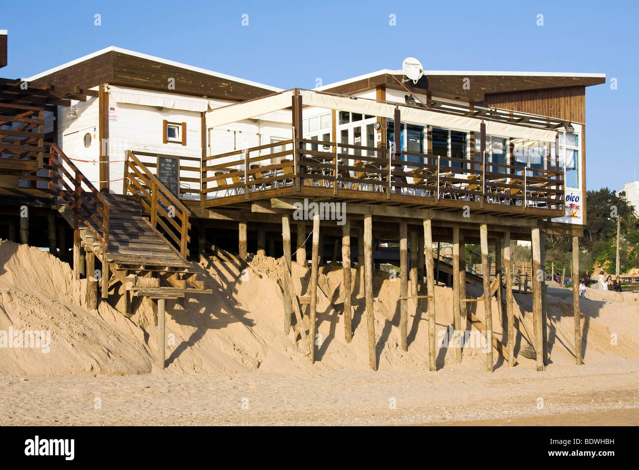 Soil erosion, beach bar on spiles nearly washed away by the sea in the sand by Algarve, Praia Alvor, Portugal, Europe Stock Photo