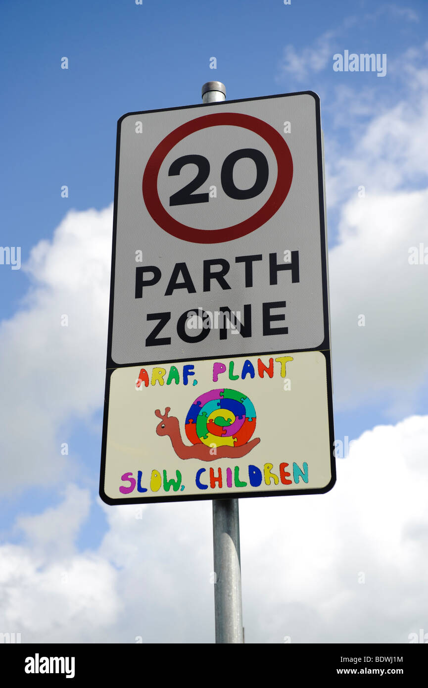20 miles per hour zone bilingual language sign, with hand painted 'slow children' snail picture in welsh and english, Wales UK Stock Photo