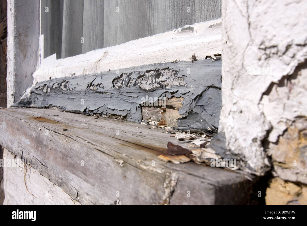 White paint peeling of an old, badly maintained, wooden windows frame