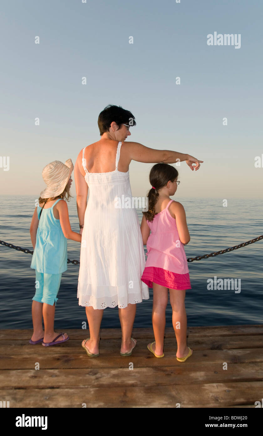 Mother and two daughters, pointing at the water Stock Photo