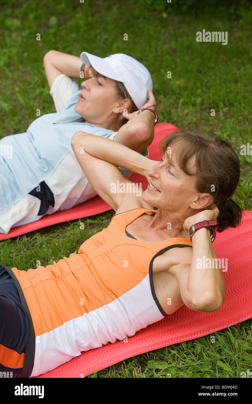 Two women do sit ups, abdominal training Stock Photo