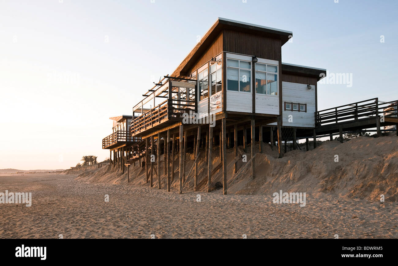 Soil erosion, beach bar on spiles nearly washed away by the sea in the sand by Algarve, Praia Alvor, Portugal, Europe Stock Photo