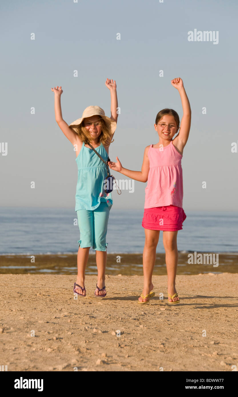Eight-year-old girls cheering on the beach Stock Photo