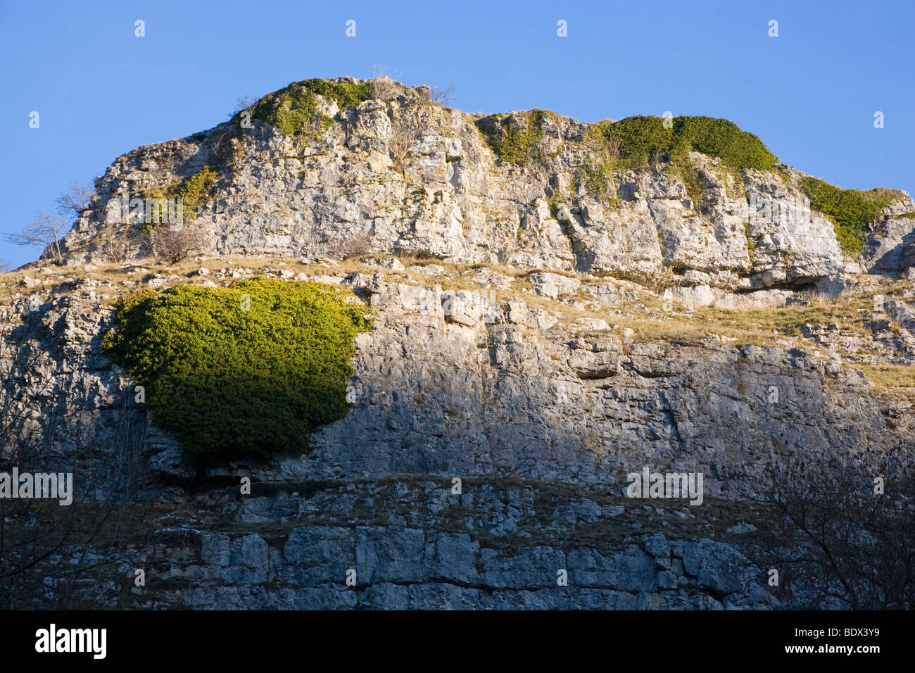 A Limestone Crag against a blue sky above Ricklow Dale at the head of Lathkill Dale in Derbyshire Stock Photo