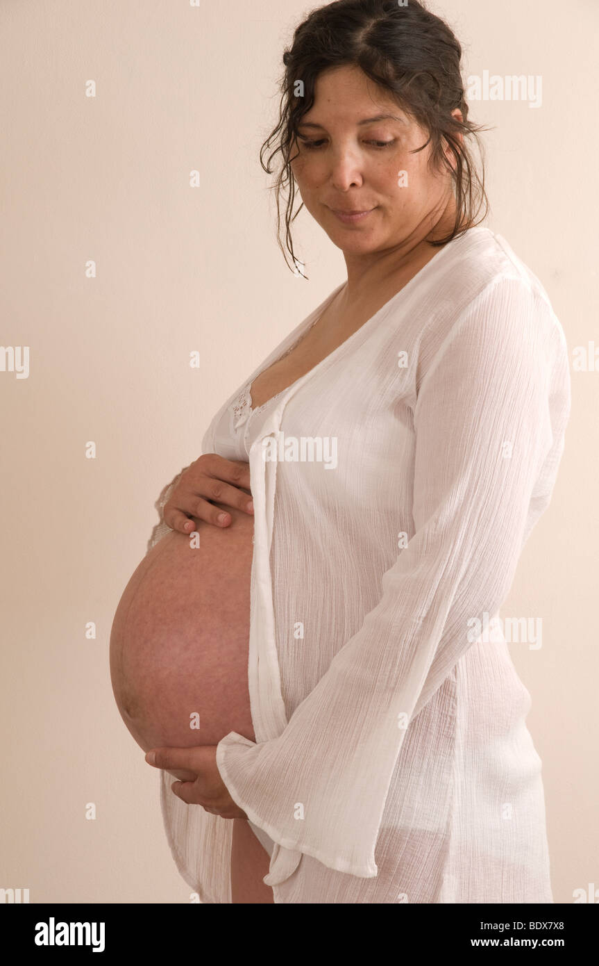 Side view of a pregnant woman with her hands resting on her tummy Stock Photo
