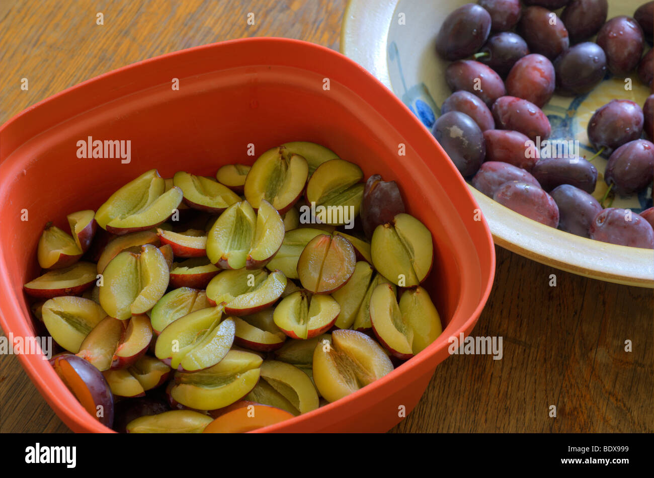 Plums being pitted and halved for a cake Stock Photo