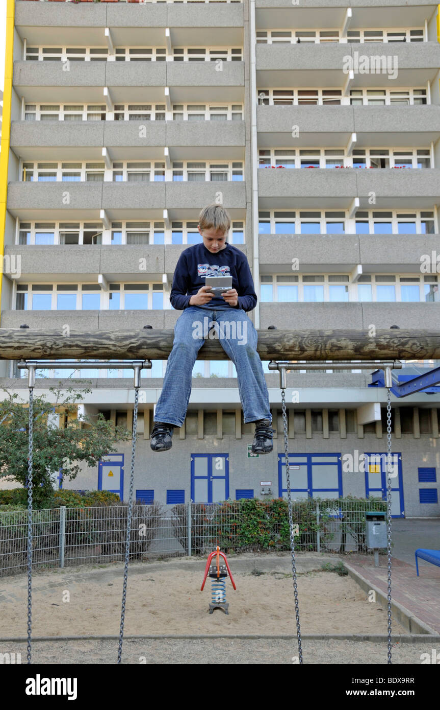 Boy, 9, playing with his Nintendo in front of a high-rise apartment building, satellite town of Chorweiler in Cologne, North Rh Stock Photo