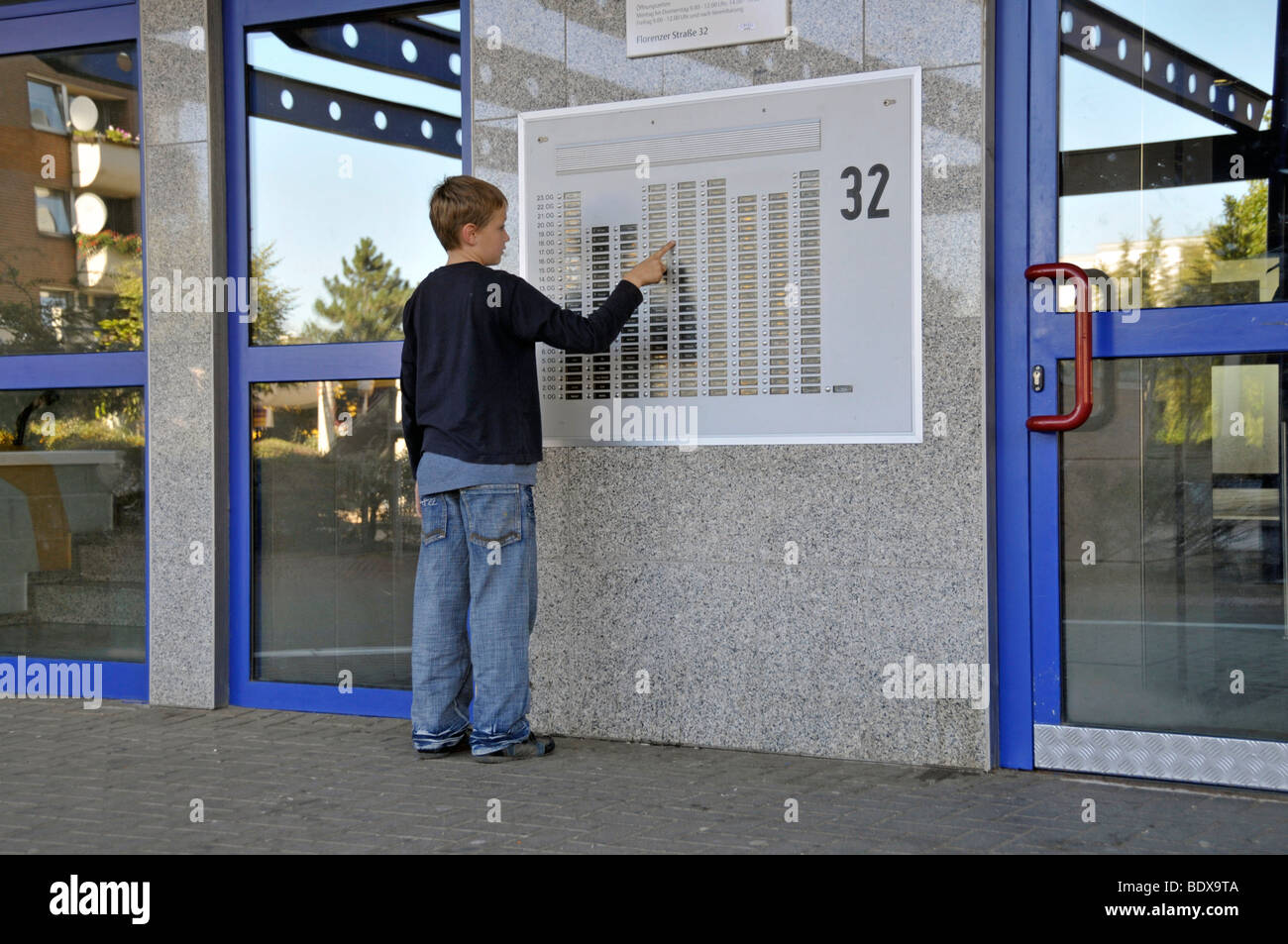 Boy, 9, standing in front of the doorbell panel of a high-rise apartment building, satellite town of Chorweiler in Cologne, Nor Stock Photo