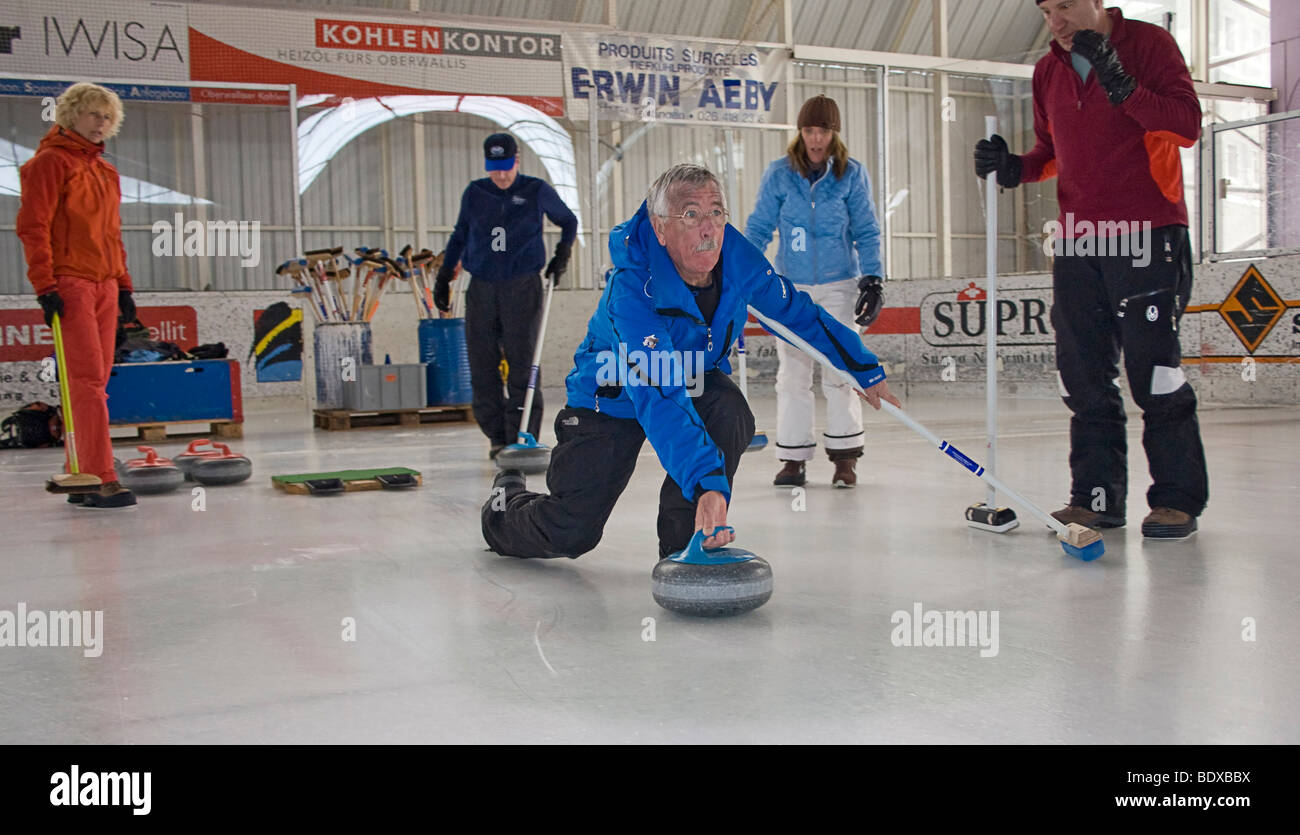 Visitors to Swiss village try curling at local ice rink. Stock Photo