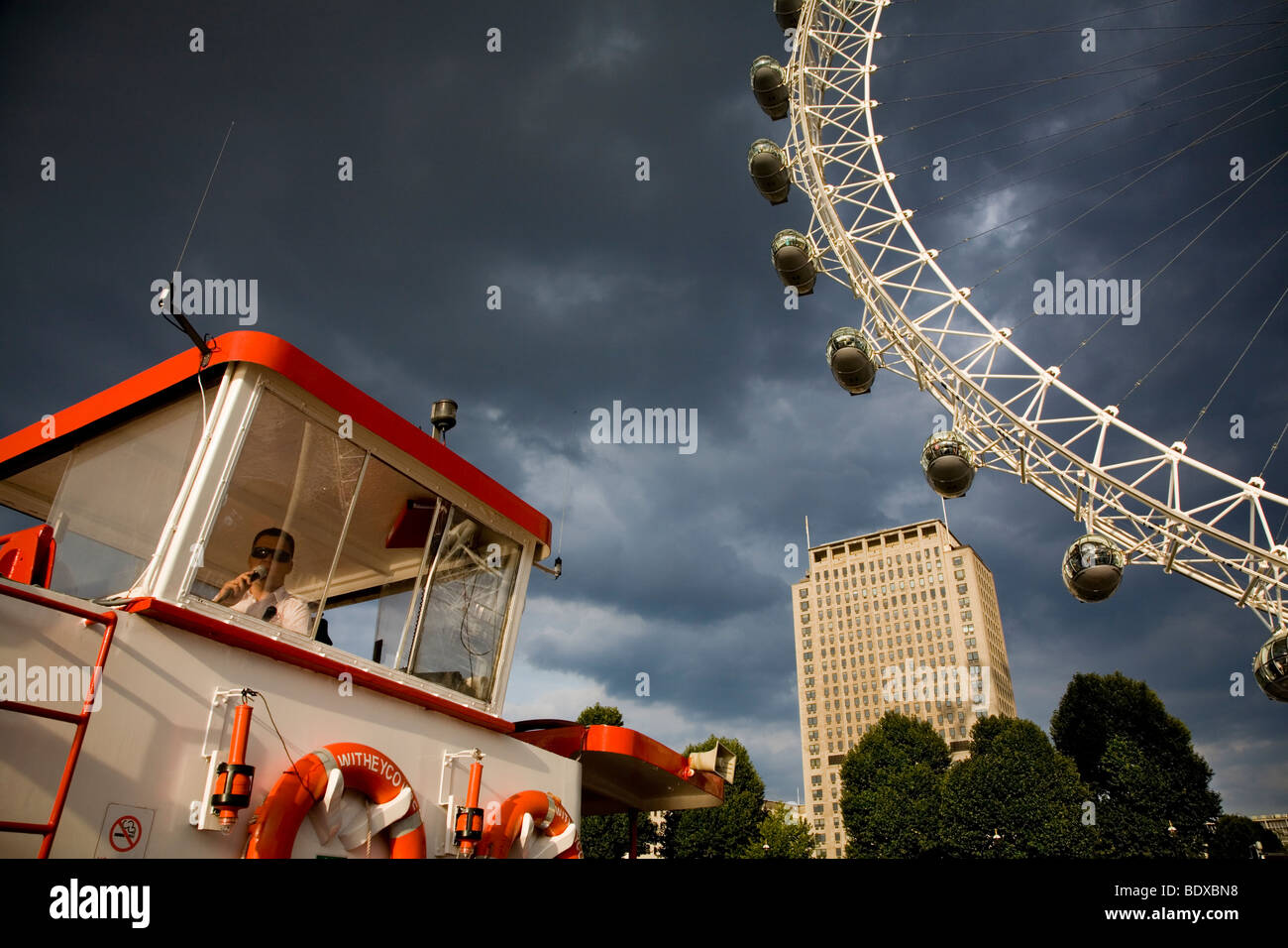 Tourist guide on river cruise boat Thame river London in front of London Eye cloudy weather summer evening before sunset Stock Photo