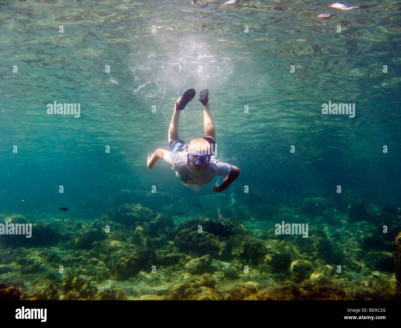 11 year old boy swimming under water. Wearing a Tshirt against the