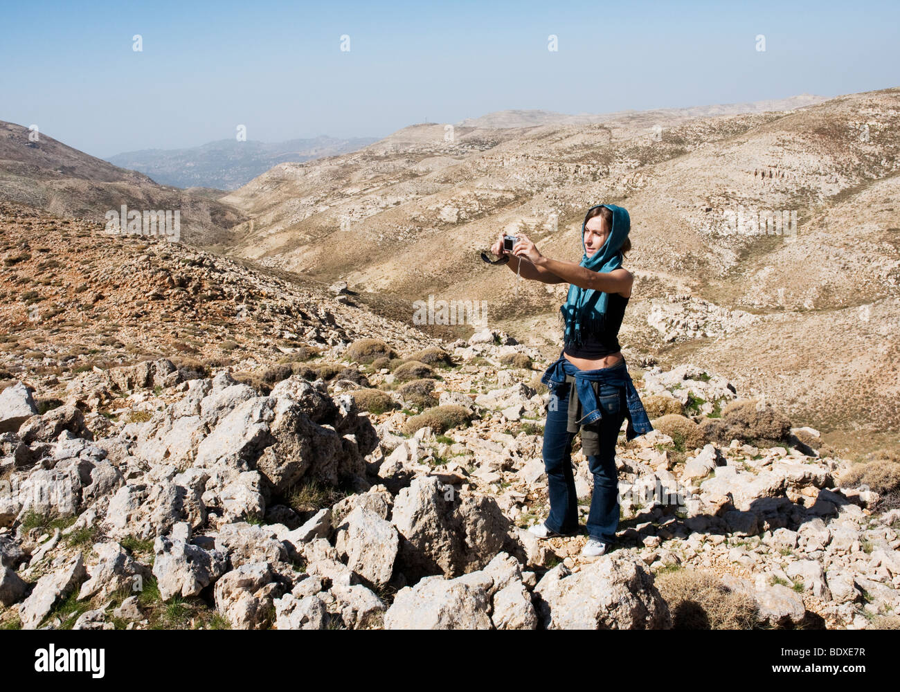 A young western woman, wearing a headscarf as protection against the sun, photographs herself in the Chabrouh mountains, Lebanon Stock Photo