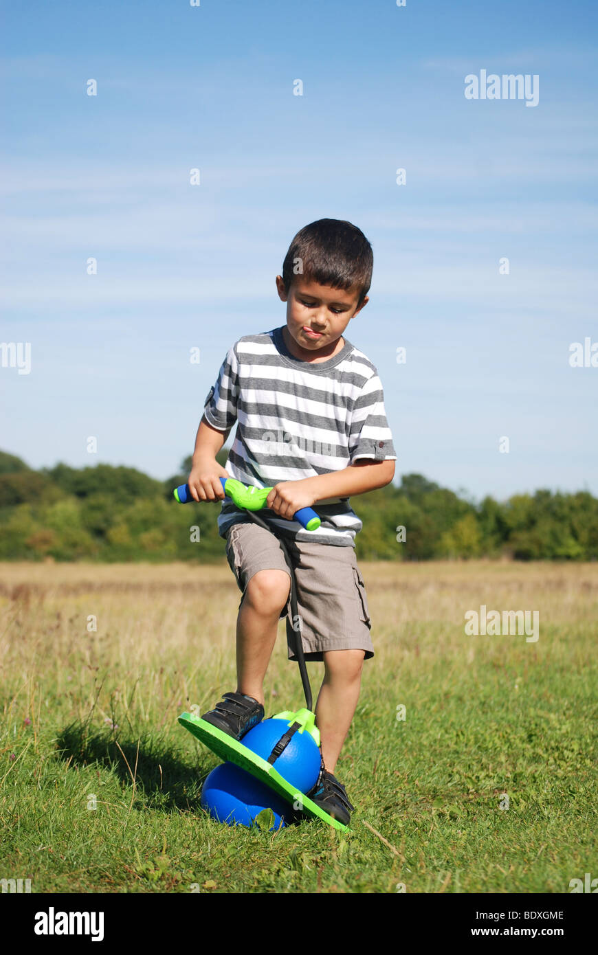 Young child playing on a bouncing ball game in the park Stock Photo Alamy