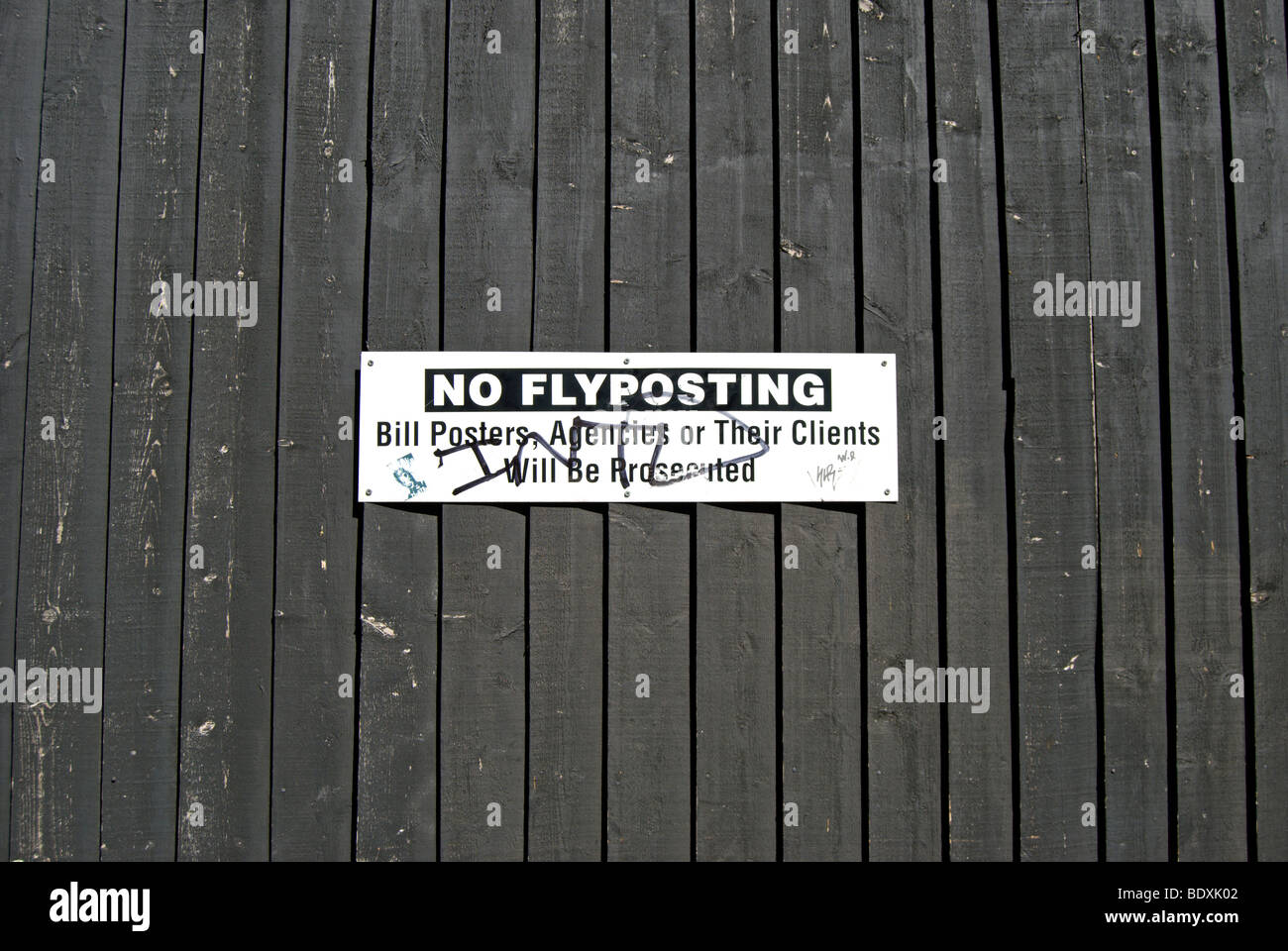 no flyposting notice, marked with graffiti, on a wooden fence in south kensington, london, england Stock Photo