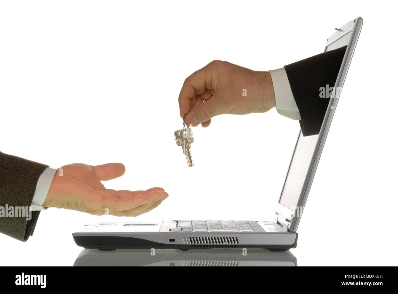 Business man giving a home key to another business man through a computer monitor, symbolic image for real estate market on the Stock Photo
