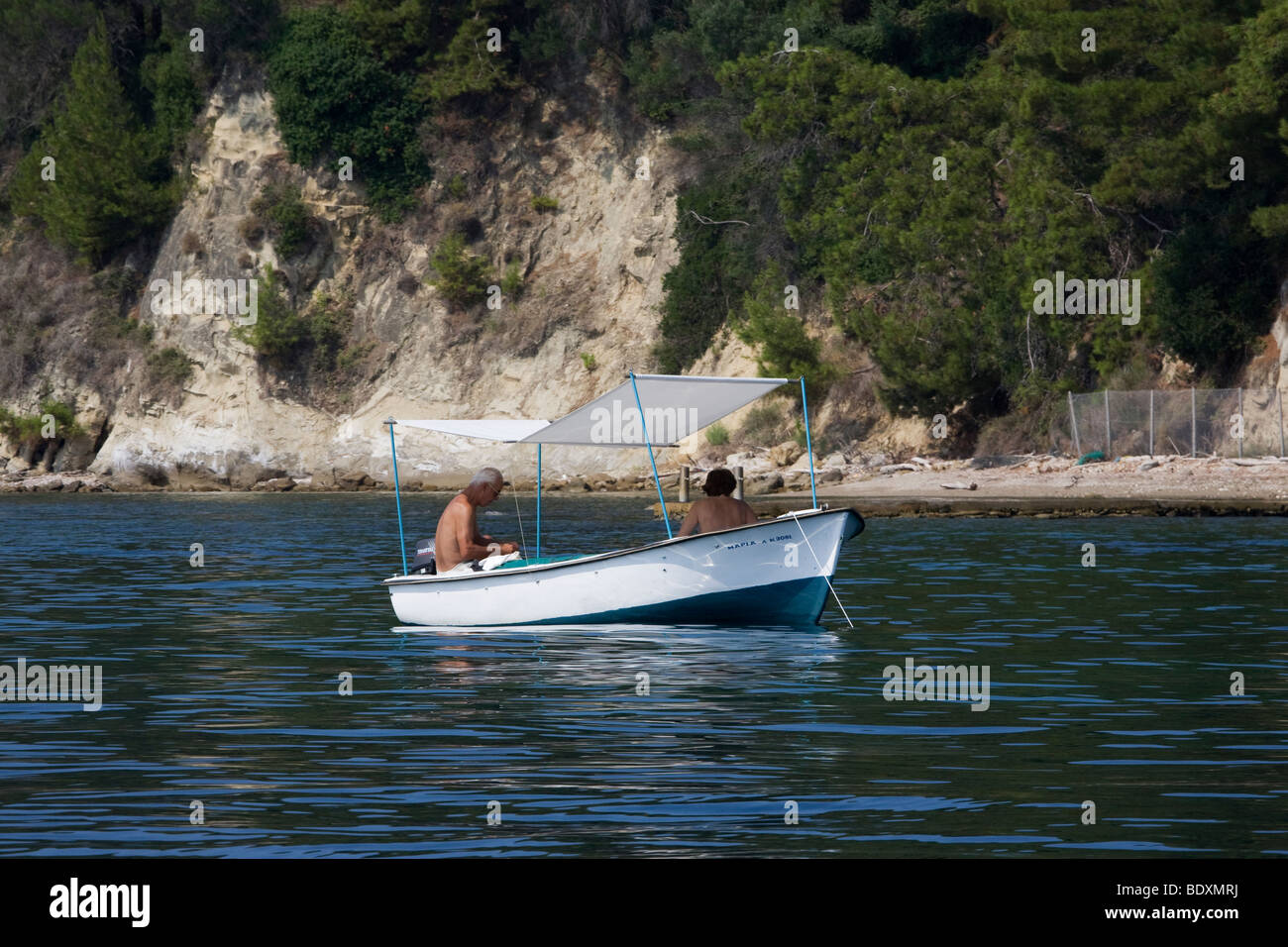 Couple in dinghy with canope of the coast of Corfu, Greece. NO Property Release. NO Model Release Stock Photo