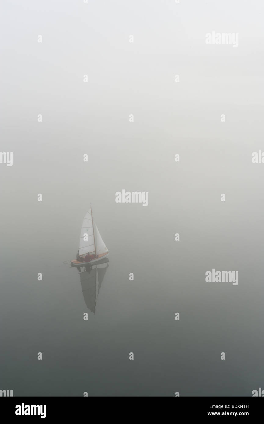 Sailboat in the fog on a lake Stock Photo
