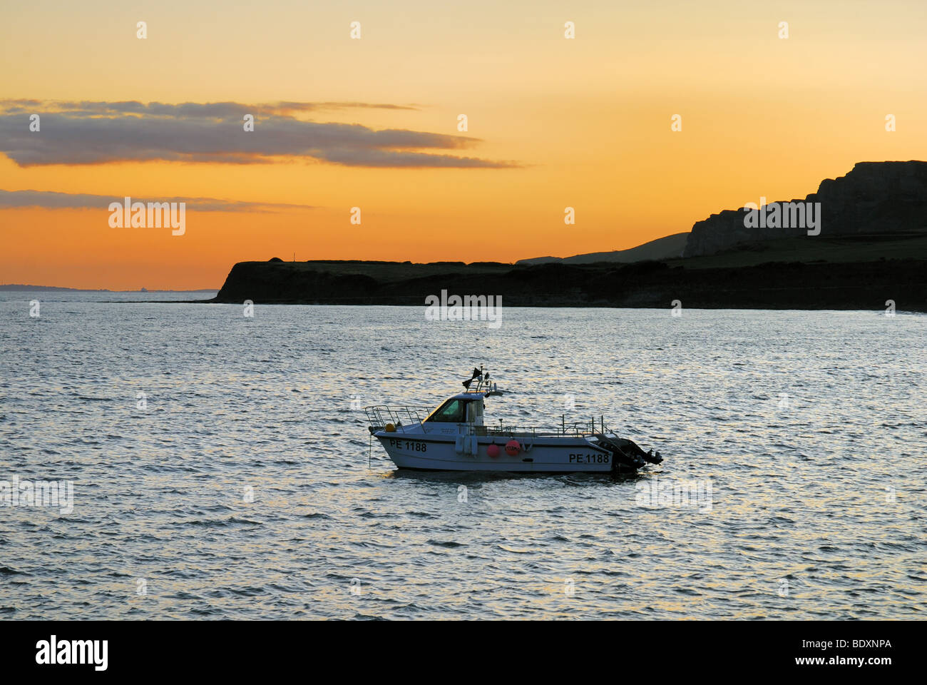 Sunset with small fishing boat Kimmeridge Bay Dorset Stock Photo