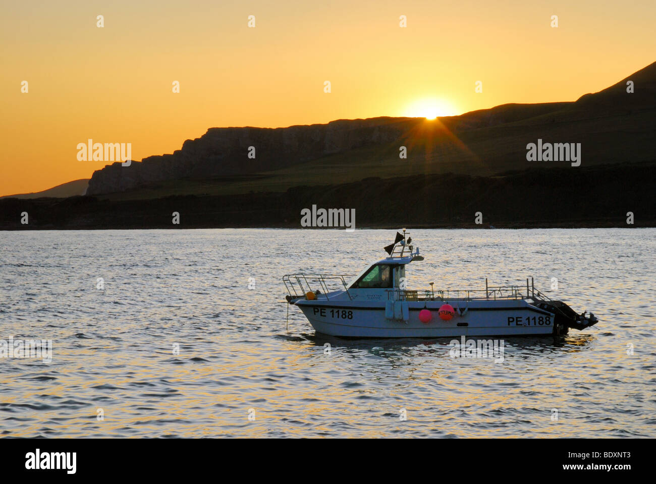 Sunset with small fishing boat Kimmeridge Bay Dorset Stock Photo