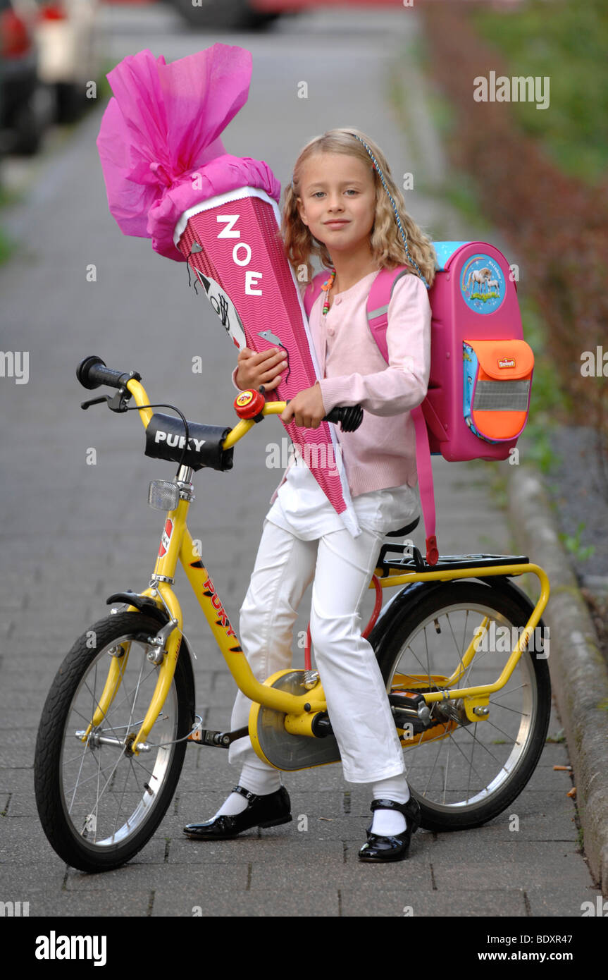 Six-year-old girl with first-day-of-school-cornet on her bike Stock Photo