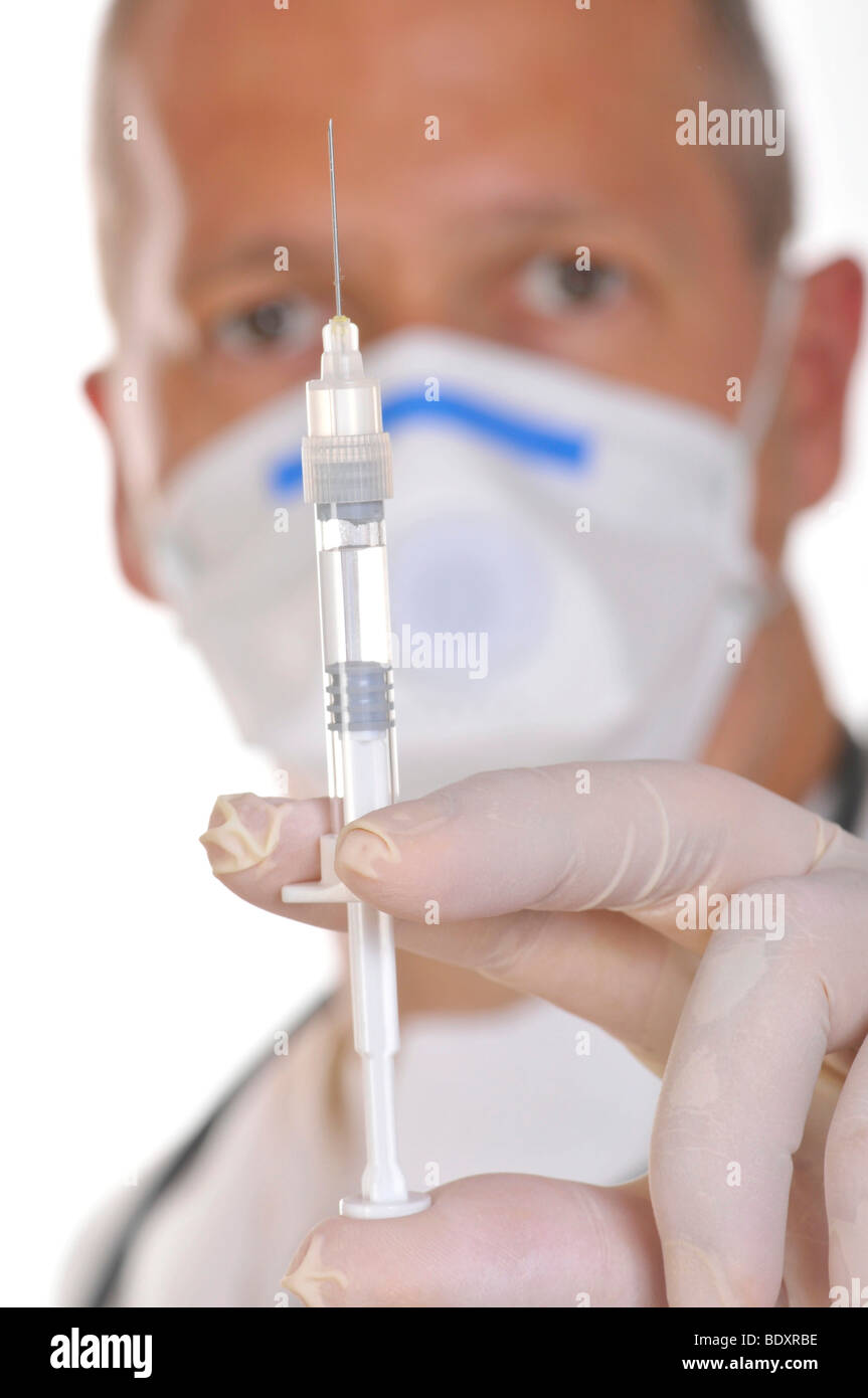 Physician wearing a virus-proof face mask, holding a syringe Stock Photo