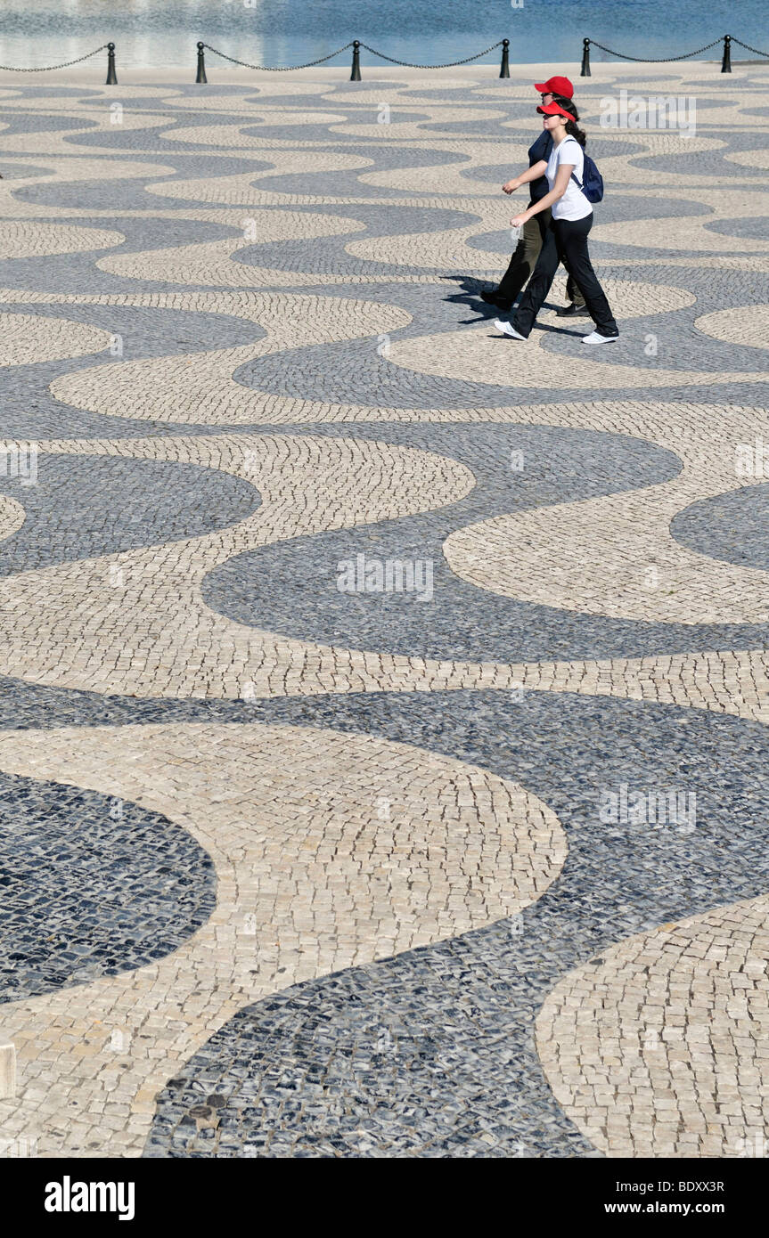 Tourists at the Tagus river, walking on cobblestone pavement with wavy pattern, Belem, Lisbon, Portugal, Europe Stock Photo
