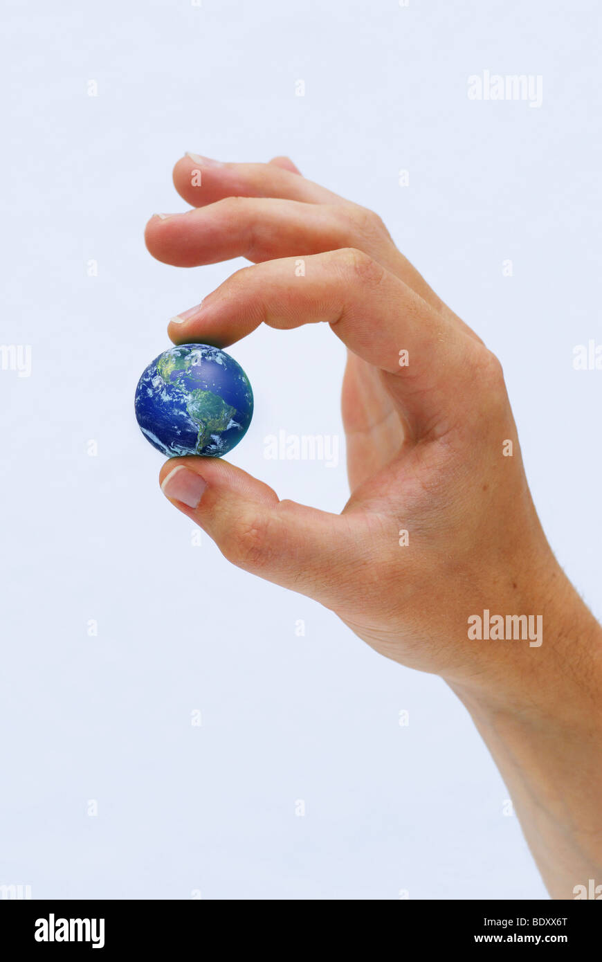 Hand holding the Earth between fingers Stock Photo