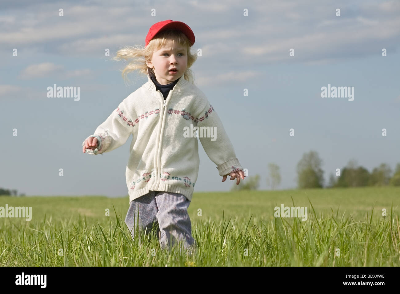 funny little girl running over green grass meadow Stock Photo