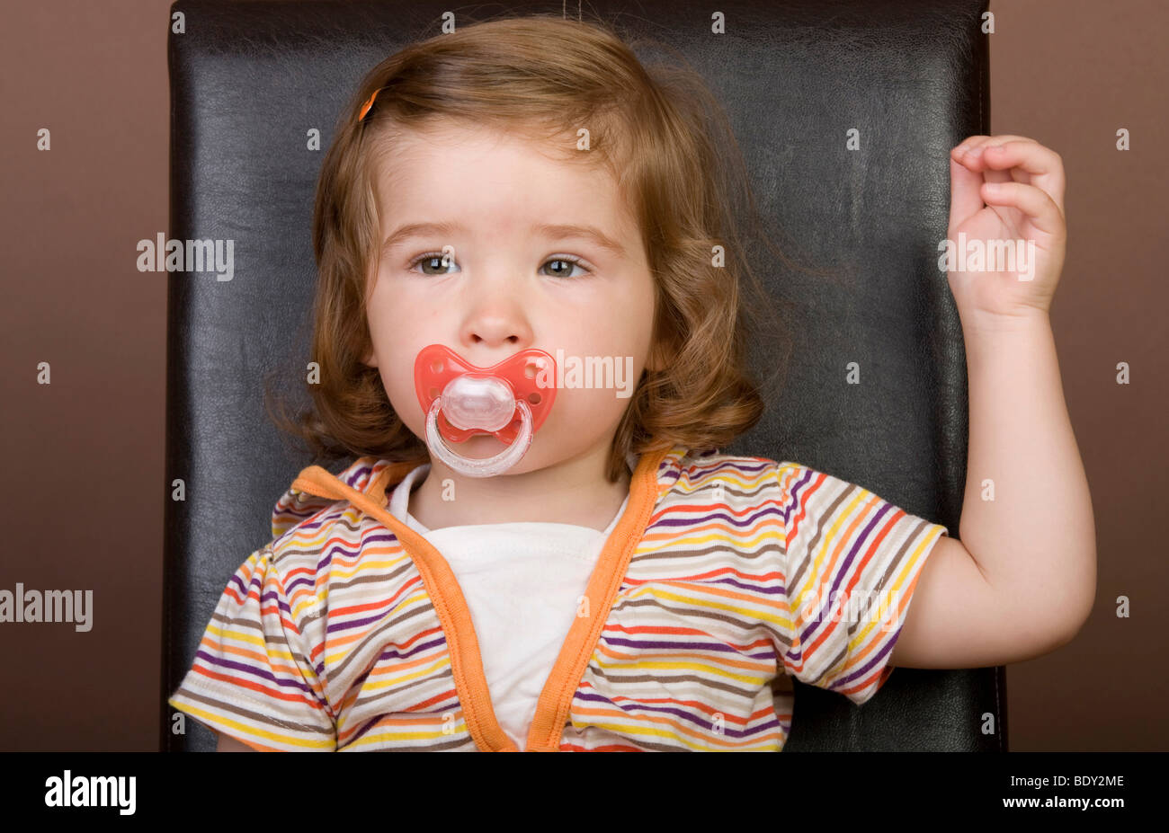Girl, 2 years, pacifier, seated, serious Stock Photo