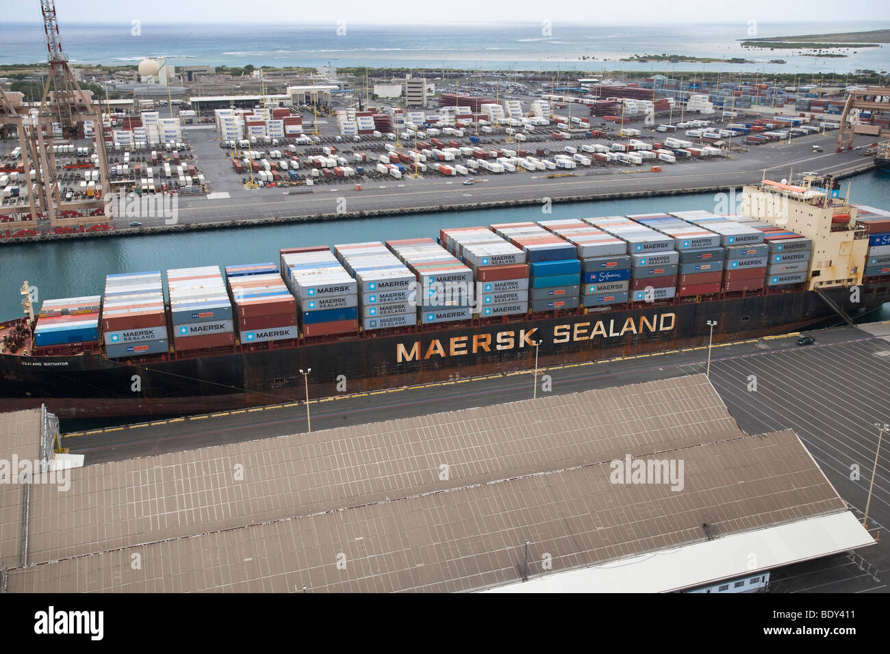 Aerial view of cargo ship carrying containerized shipping and container handling area of Sand