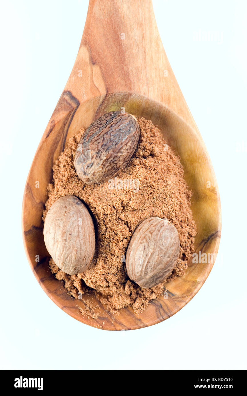 Nutmegs (Myristica fragrans), whole and powdered on a spoon of olive wood Stock Photo