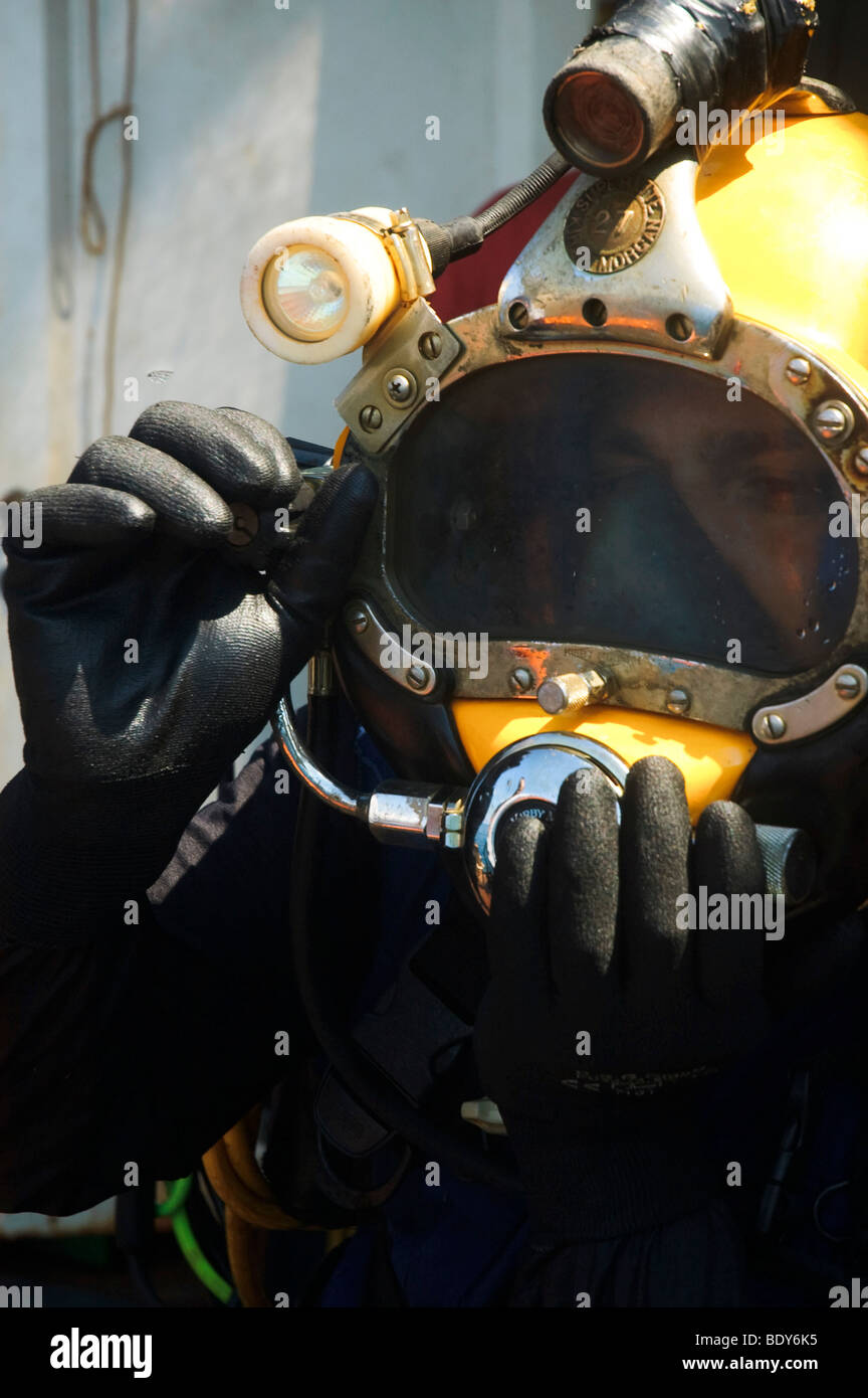 Commercial diver gets ready for a dive The diver is using a helmet connected to an air supply on his back Stock Photo
