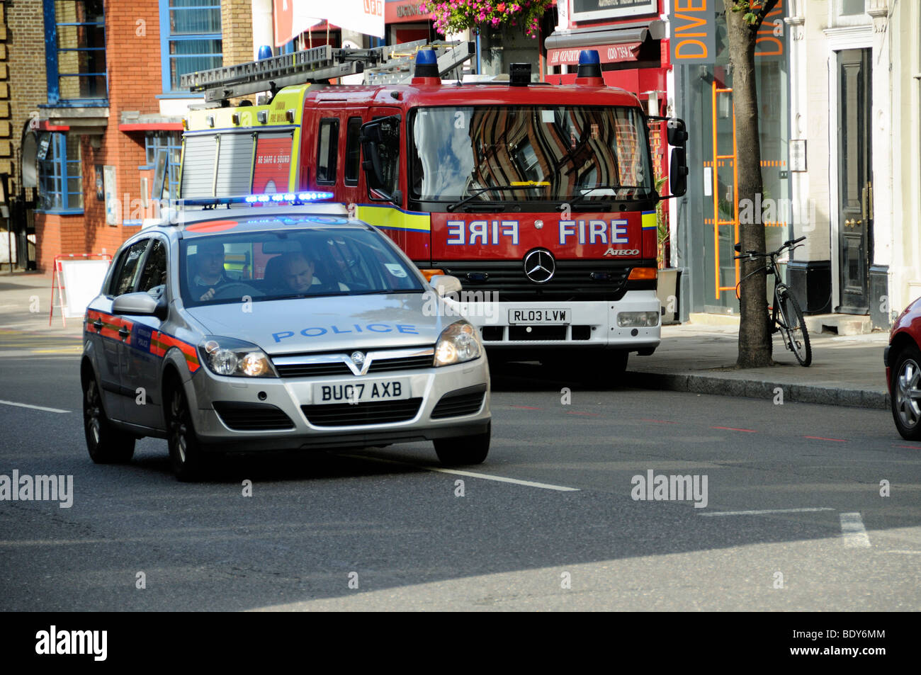 Police car with flashing lights passing fire engine, Upper Street