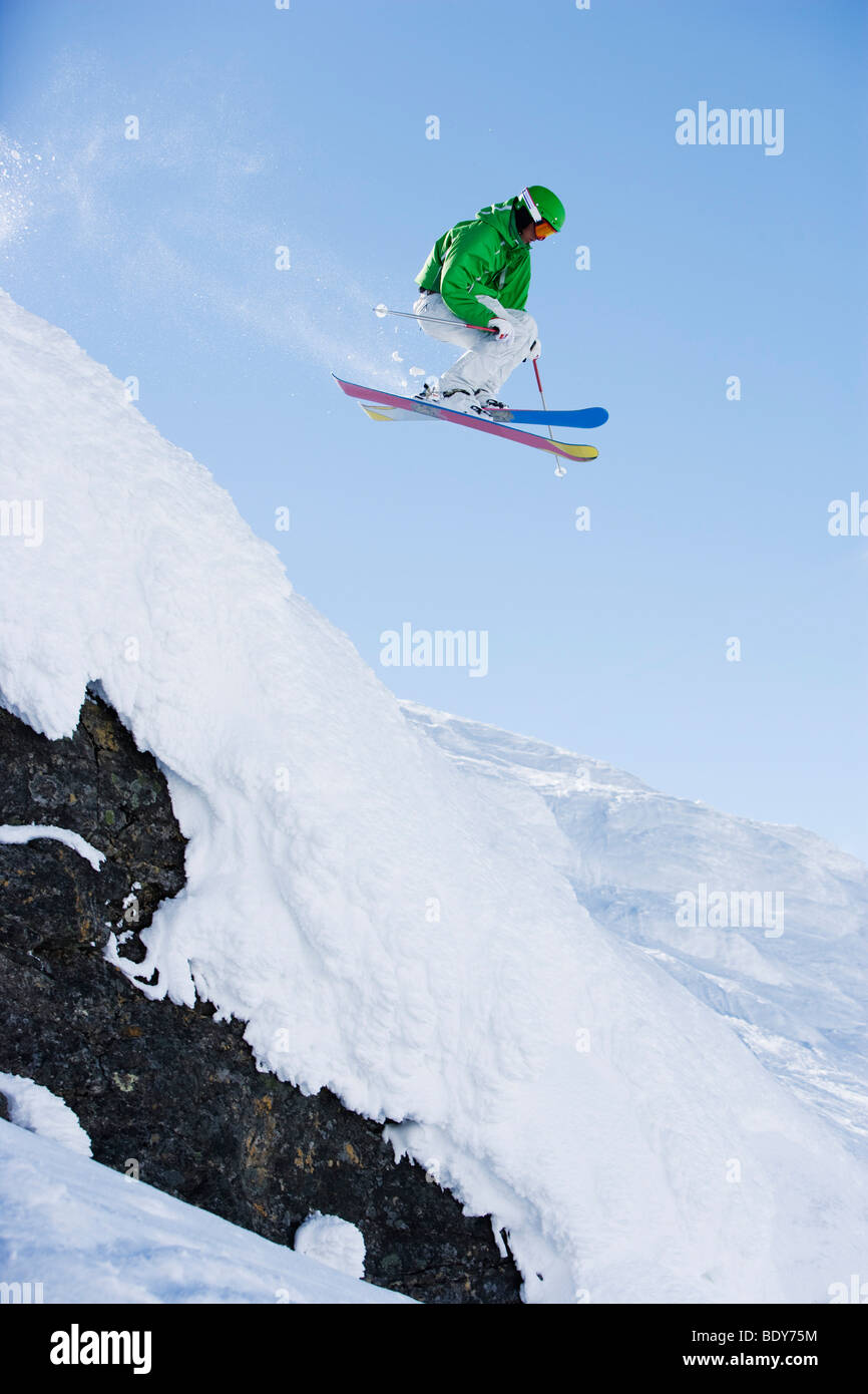 Man in green dropping a cliff face. Stock Photo