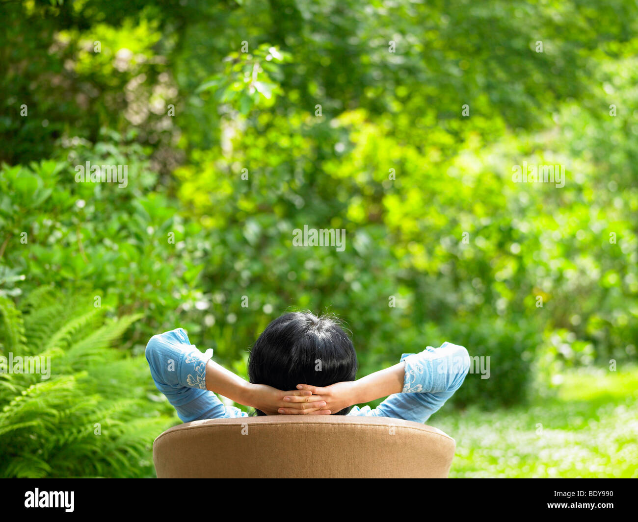 Woman on sofa, in the garden Stock Photo