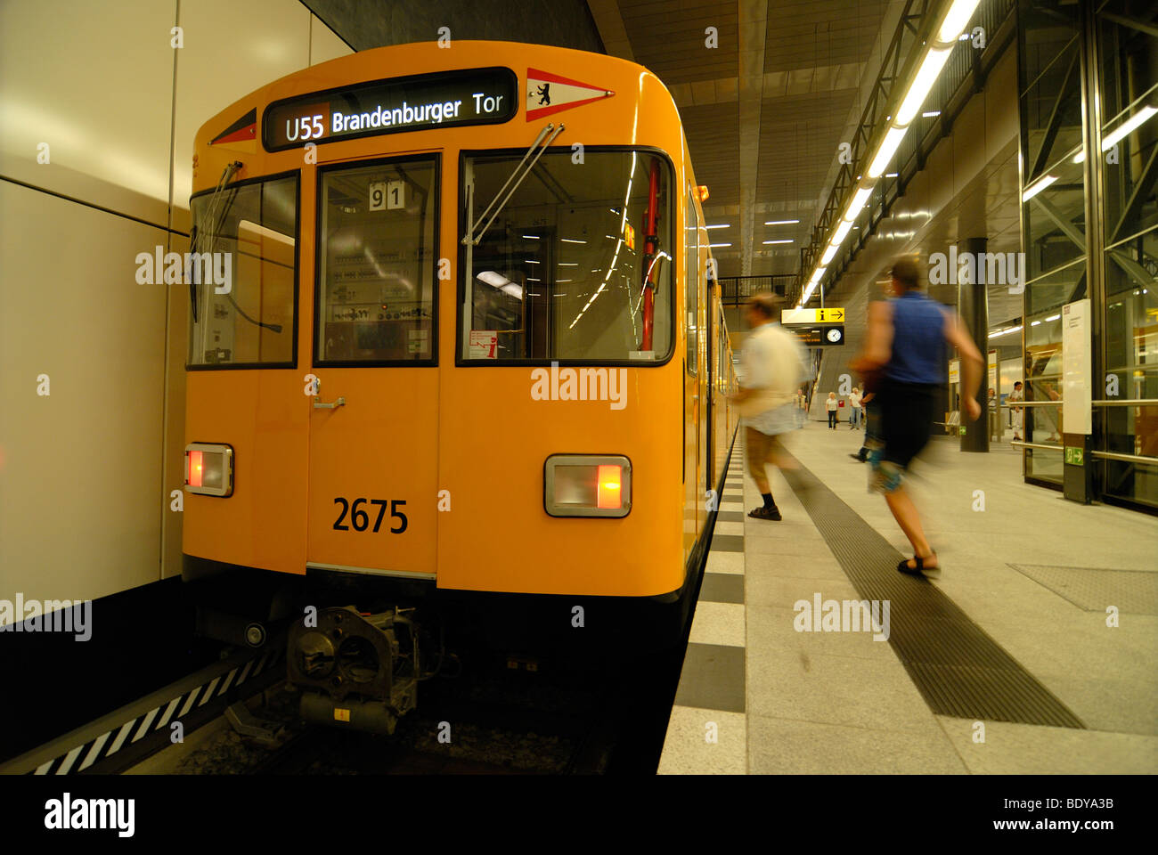 Two passengers running to the new subway line U55, with a traditional yellow subway carrriage, Brandenburger Tor Station, Berlin Stock Photo