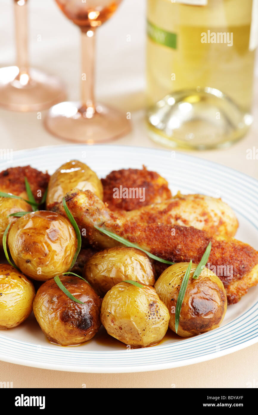 Roasted chicken legs with baked potatoes and white wine Stock Photo