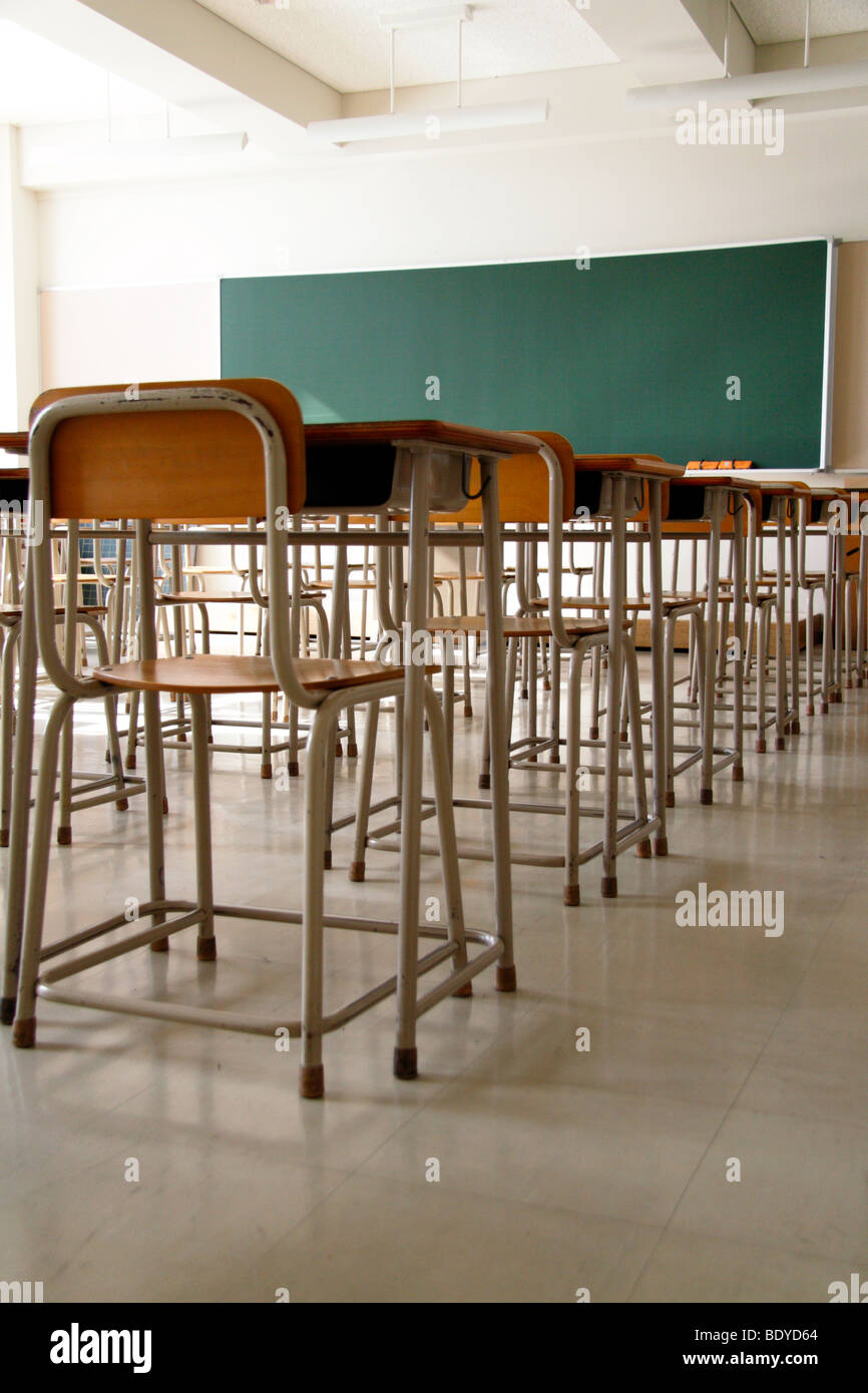 Empty classroom due to shutdown. Only school desks, chairs and a blackboard. No students. Stock Photo