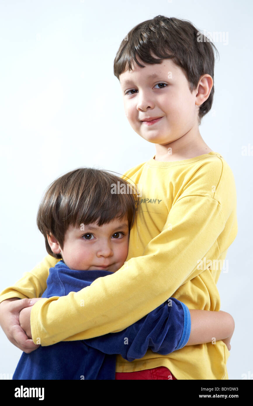 Six-year-old boy hugging his three-year-old sister Stock Photo