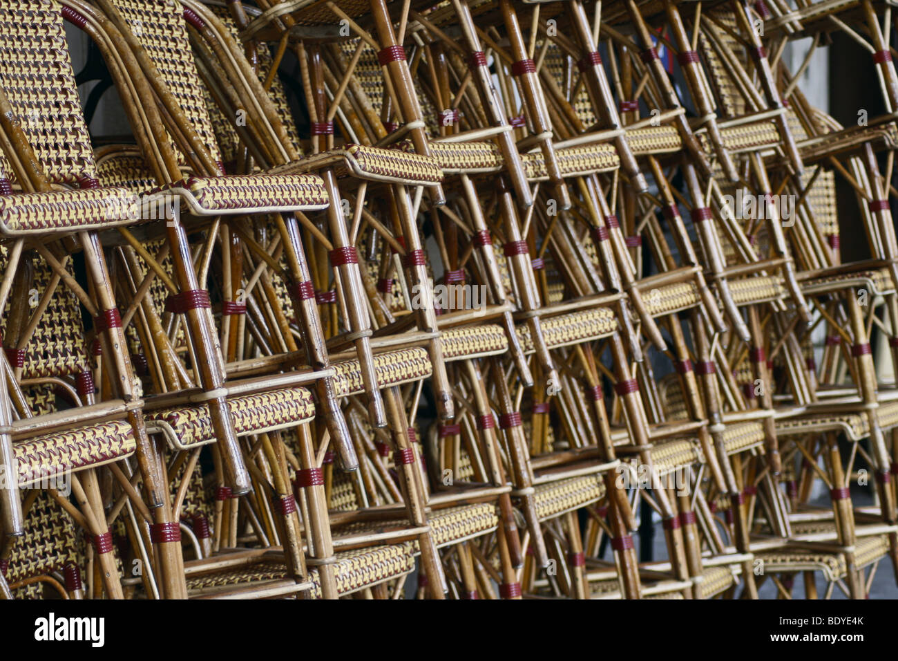 A lot of stacked wicker chairs in a line Stock Photo