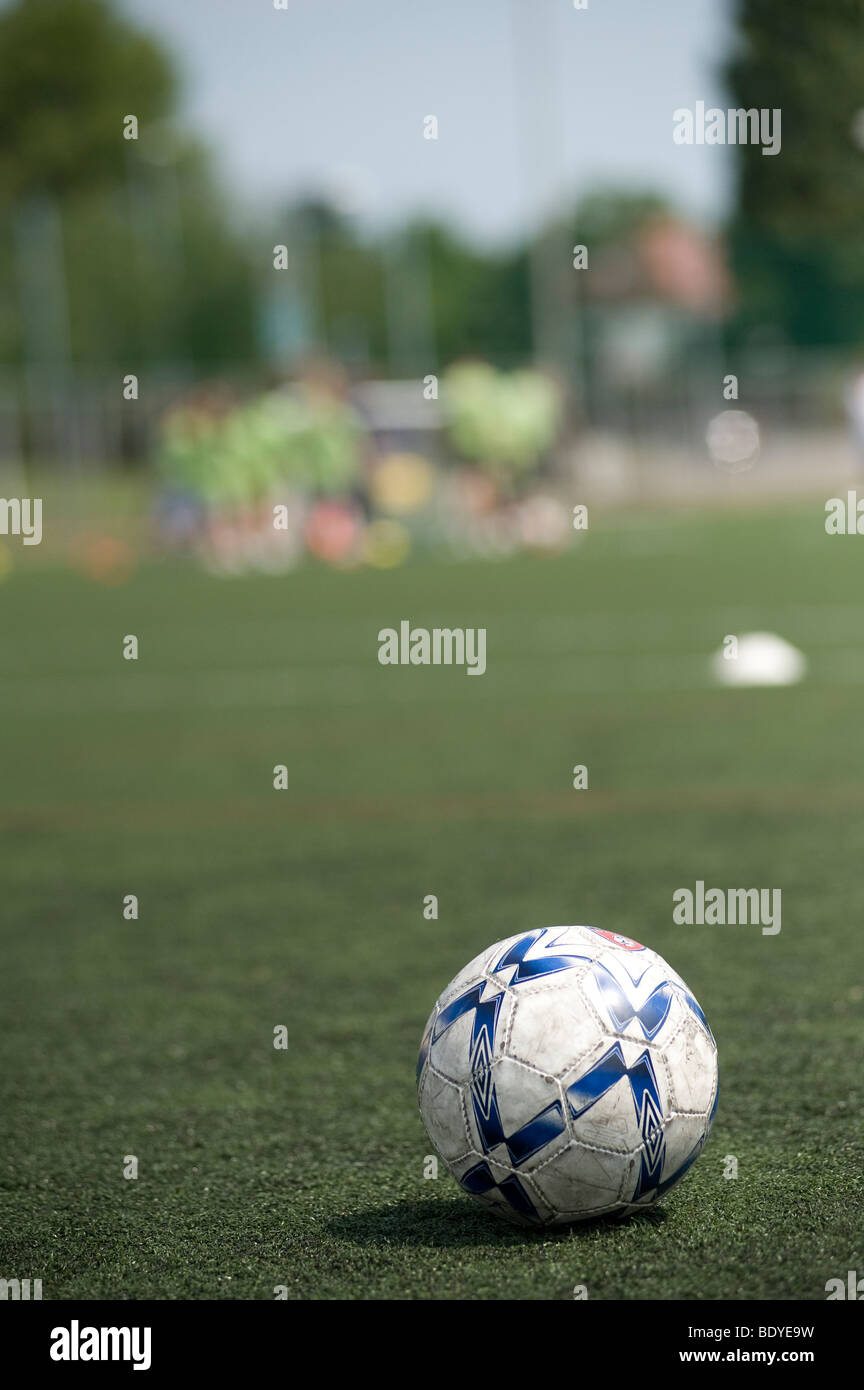 Footballs on a playing field with team in the background Stock Photo