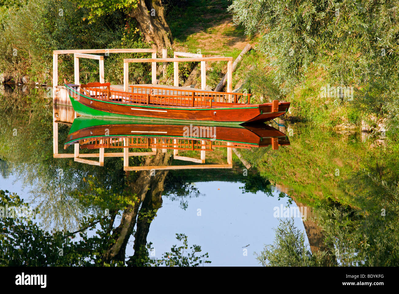 Wooden row boat by the river bank tied to the small wooden pier Stock ...