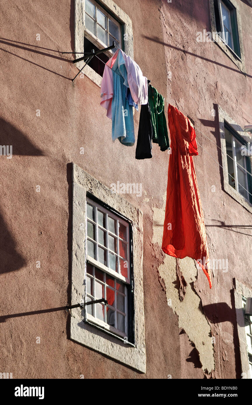 Laundry hanging to dry on a line in front of a house with crumbling plaster walls in the district of Alfama, Lisbon, Portugal,  Stock Photo