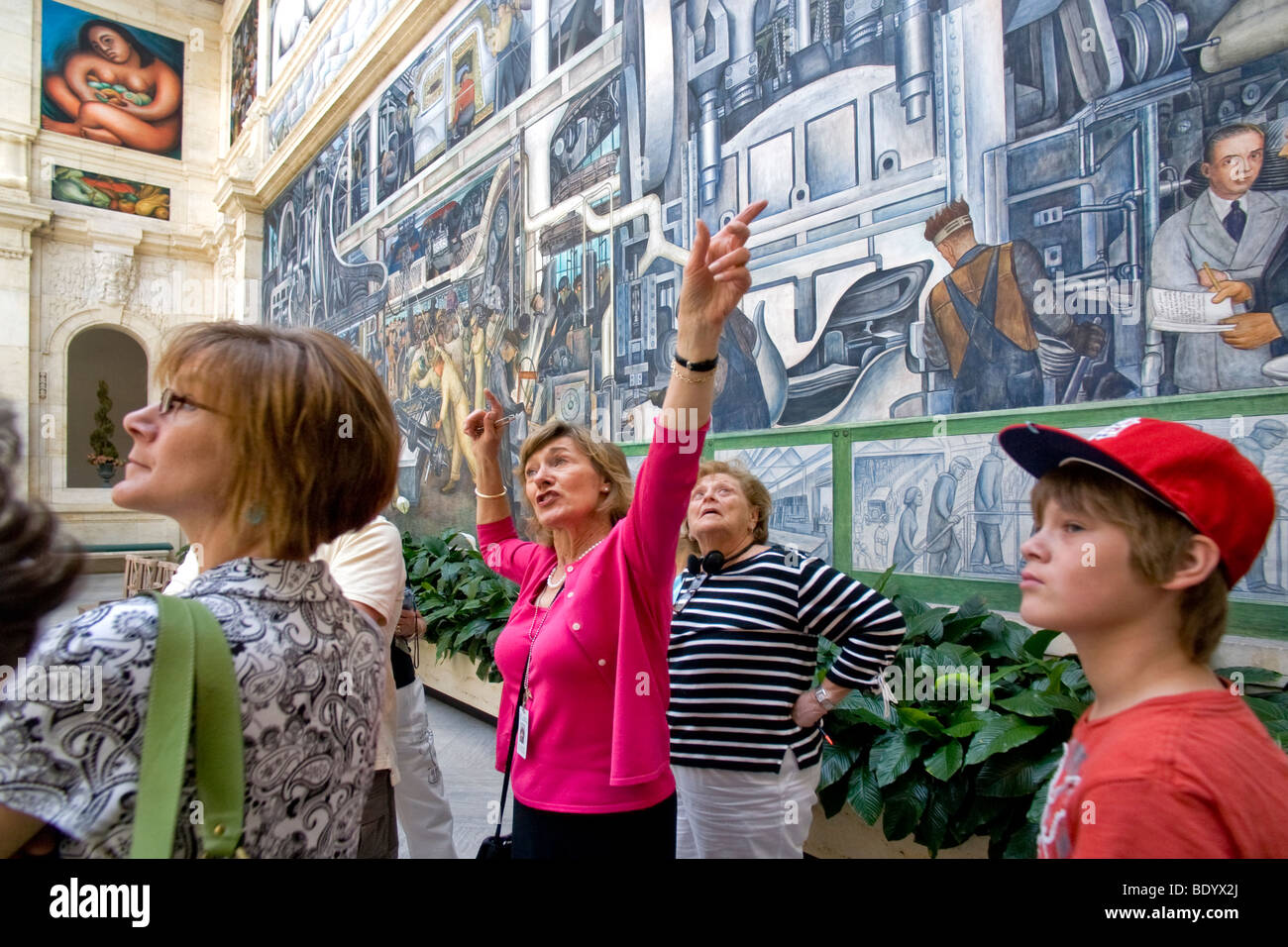 A Detroit Institute of Art docent explains the museum's famous Diego Rivera murals of the Ford Rouge Plant to a tourist group. Stock Photo